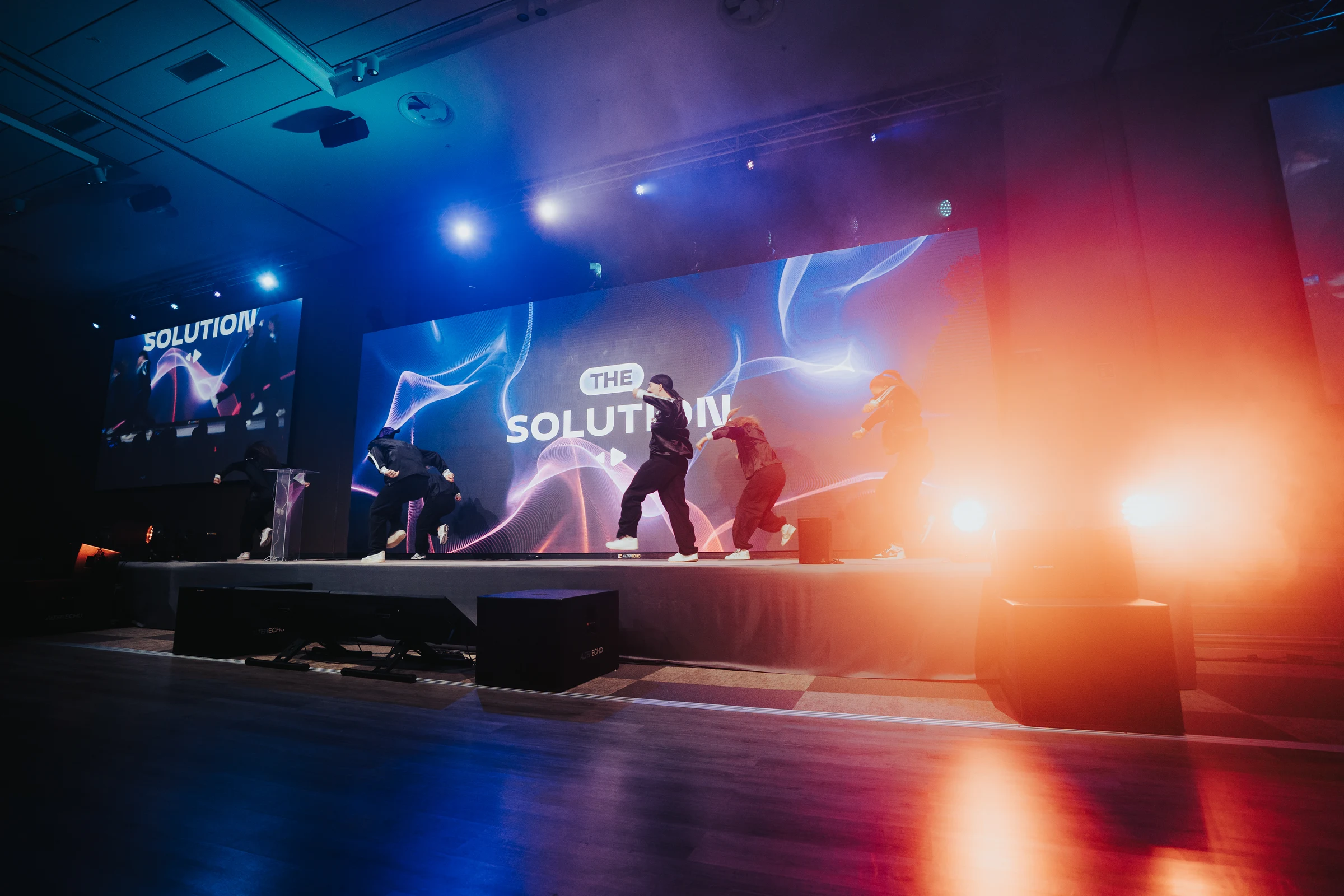 Dance crew on an illuminated conference stage