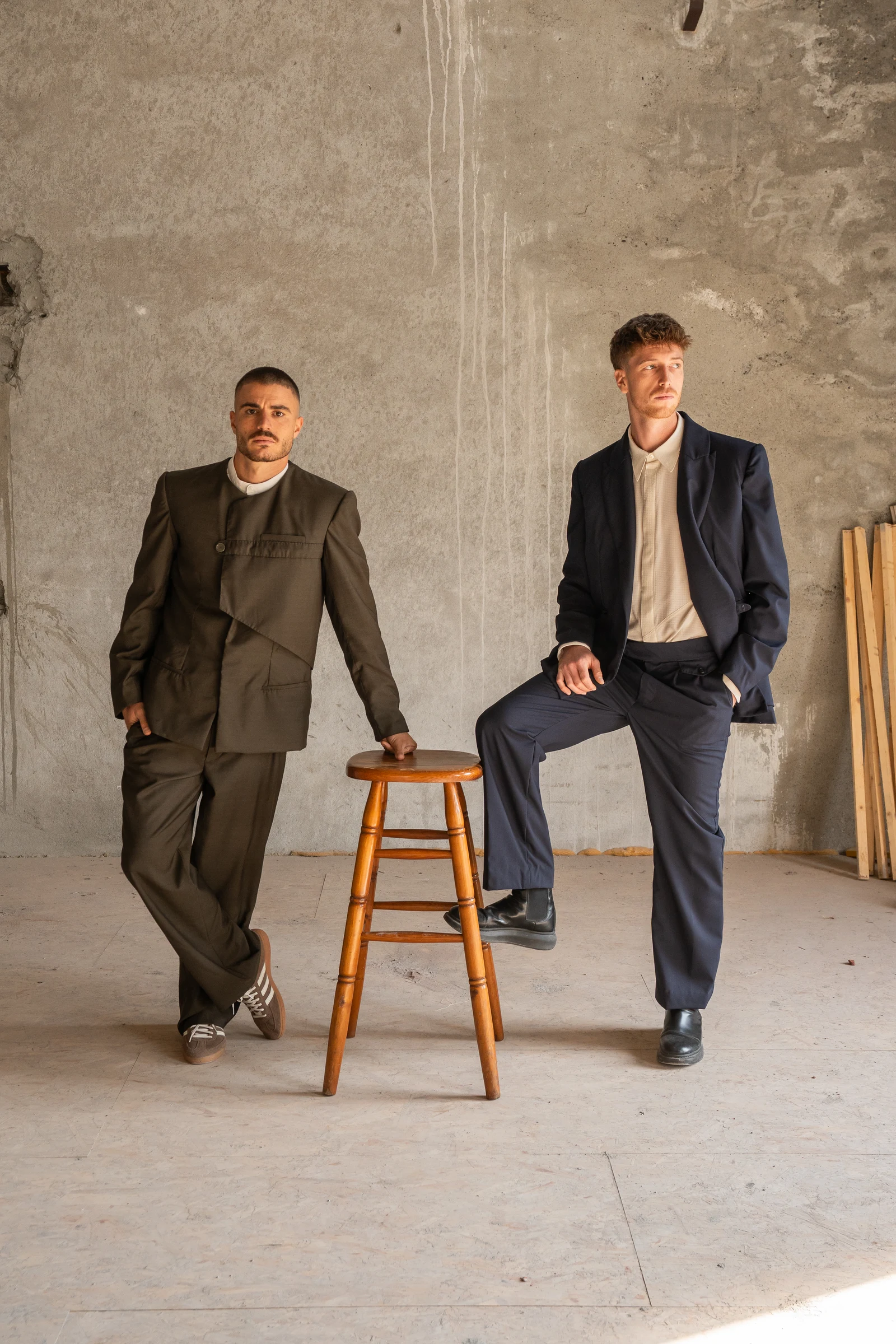 Two male models in suits inside a raw studio