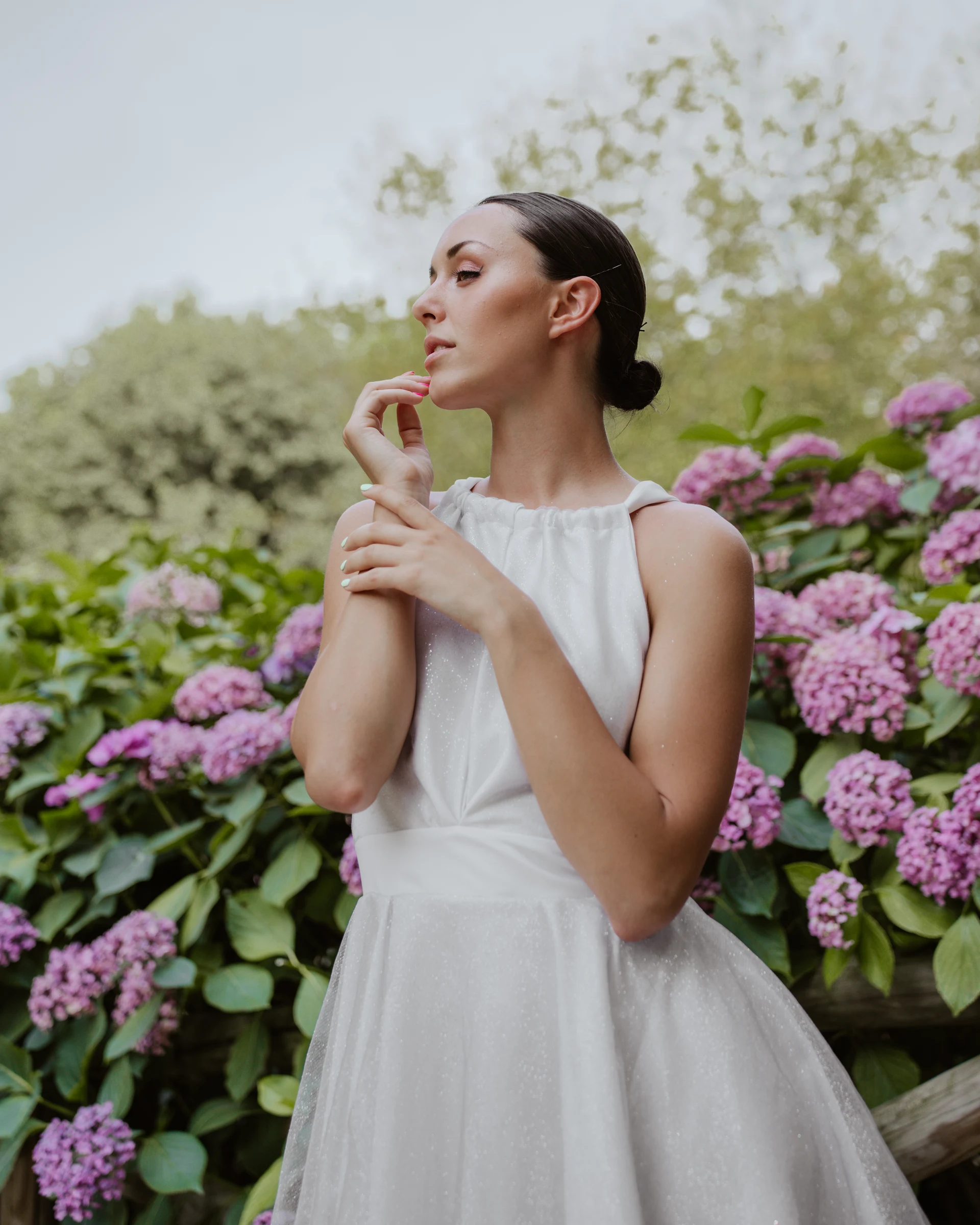 Model in a white wedding dress standing in front of hydrangeas