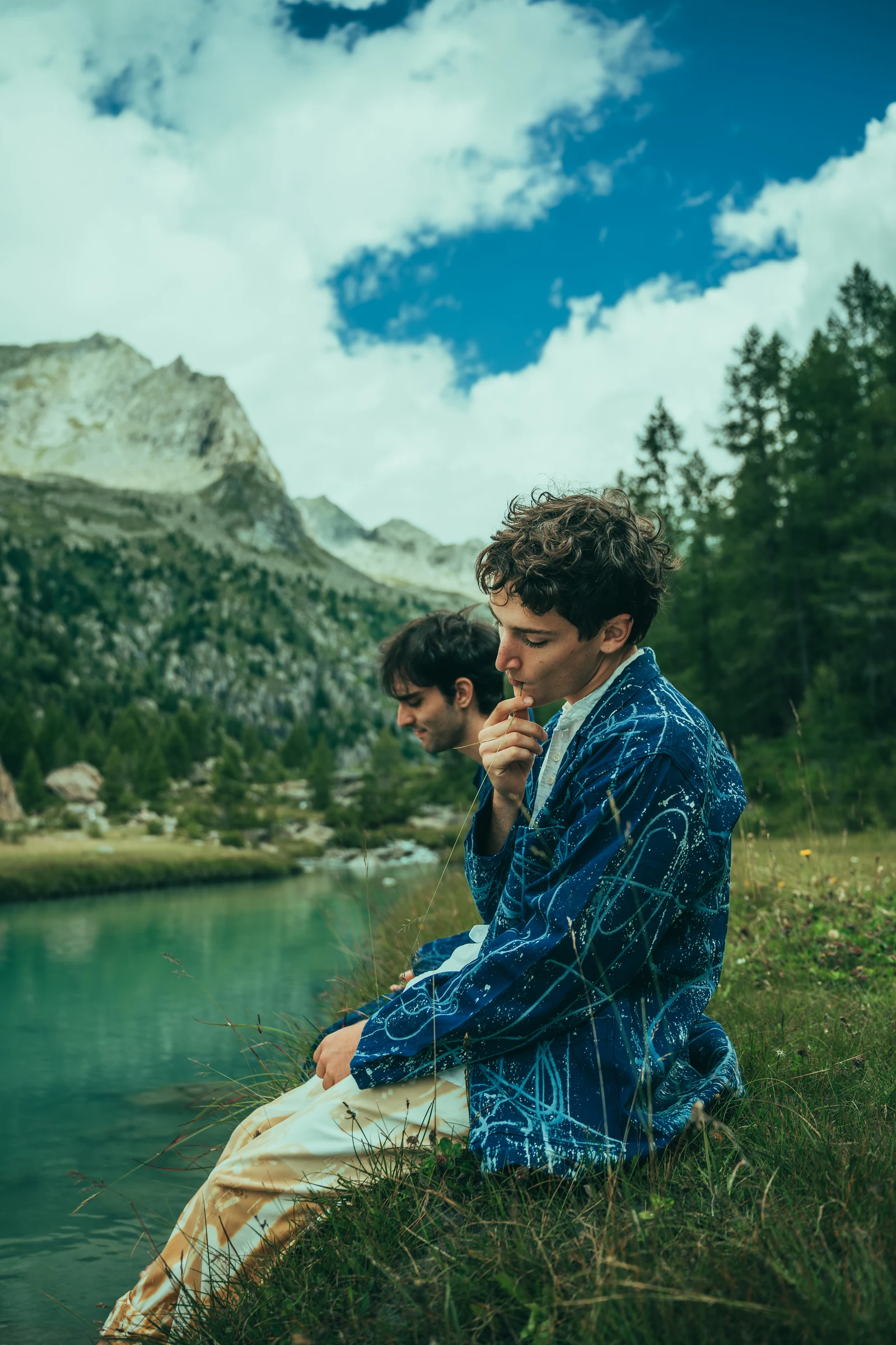Male model in a blue jacket beside a mountain lake