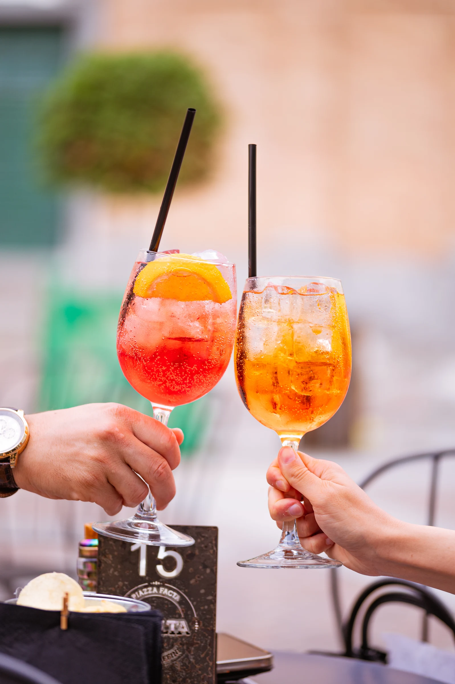 Two glasses of spritz raised on a terrace