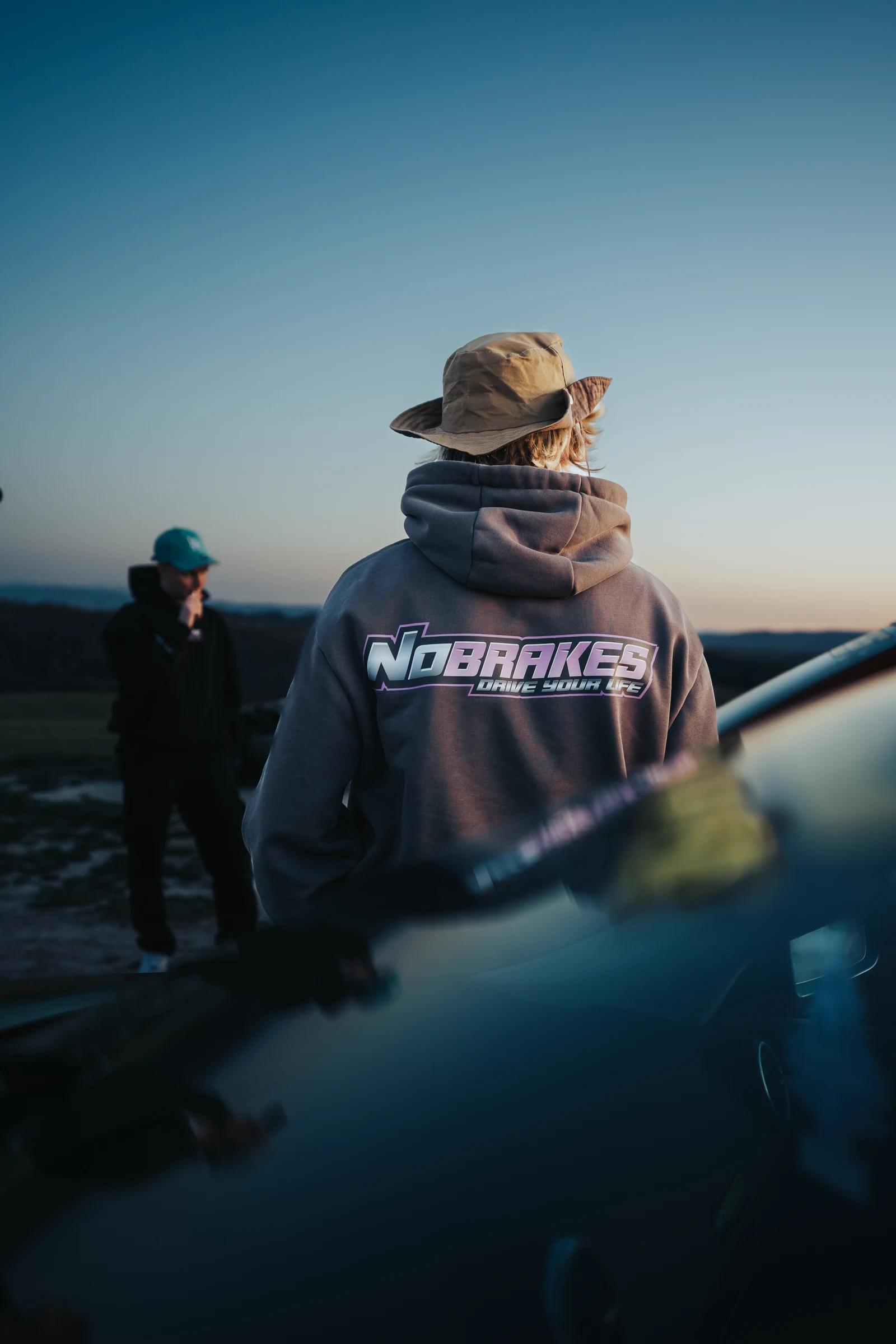 Portrait of a man in a hat beside a sports car