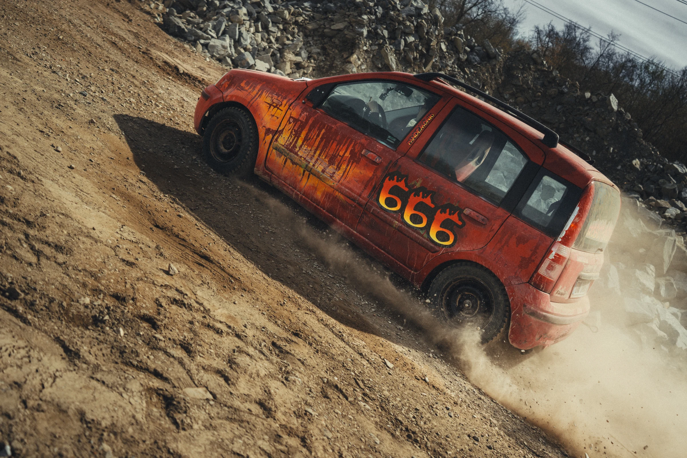 Red rally car climbing a dusty slope