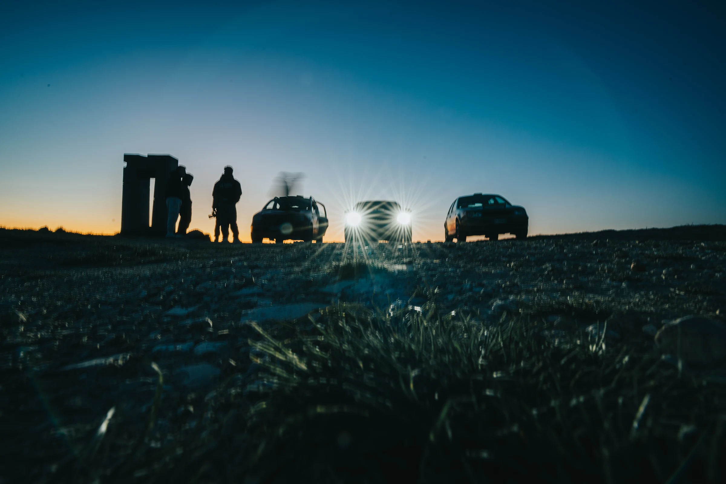 Silhouettes and rally cars illuminated on the horizon