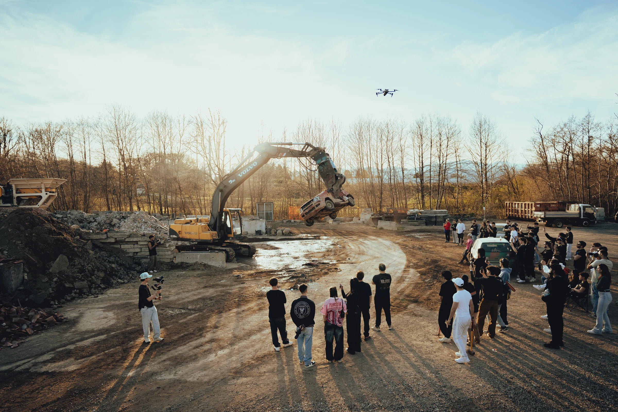 Car lifted by an excavator during an outdoor automotive production