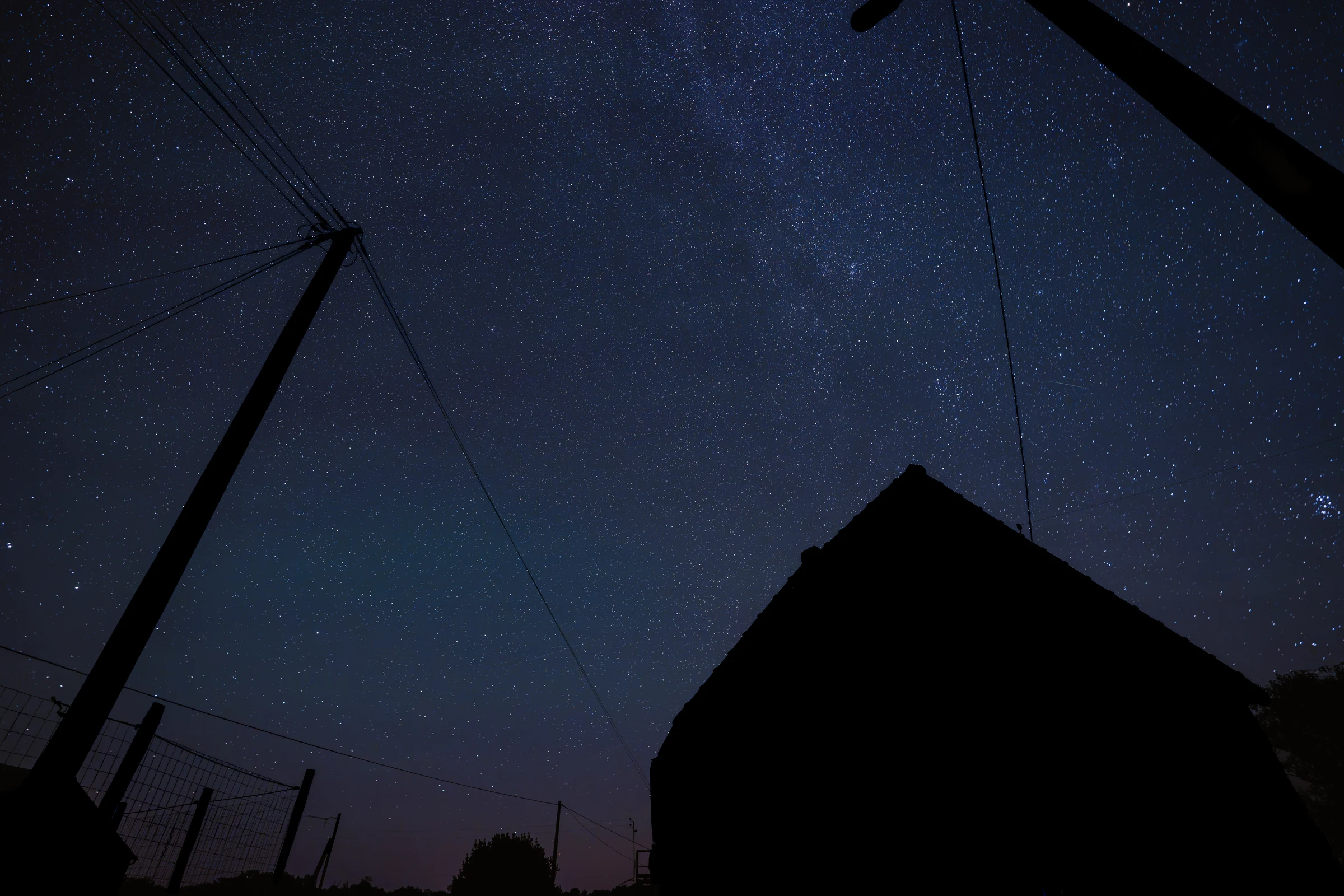 Star-filled night sky above a dark building silhouette