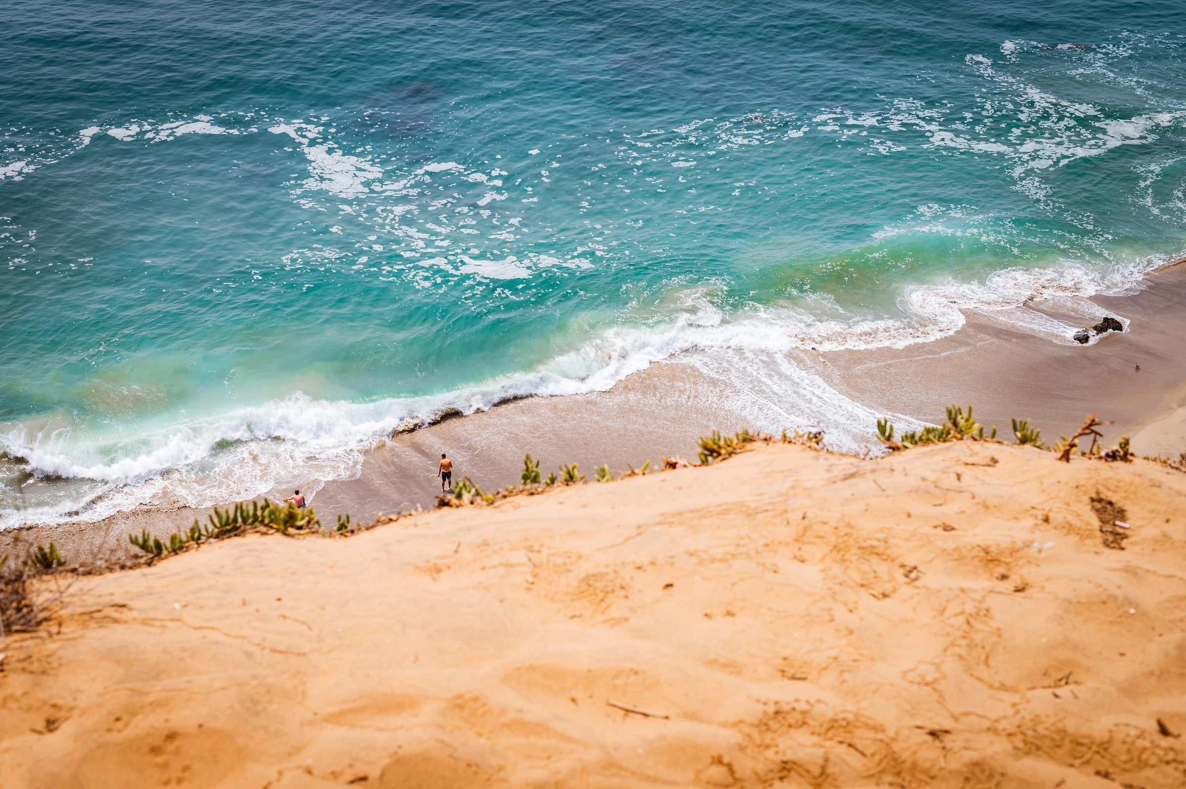 Ochre sand beach beside turquoise water