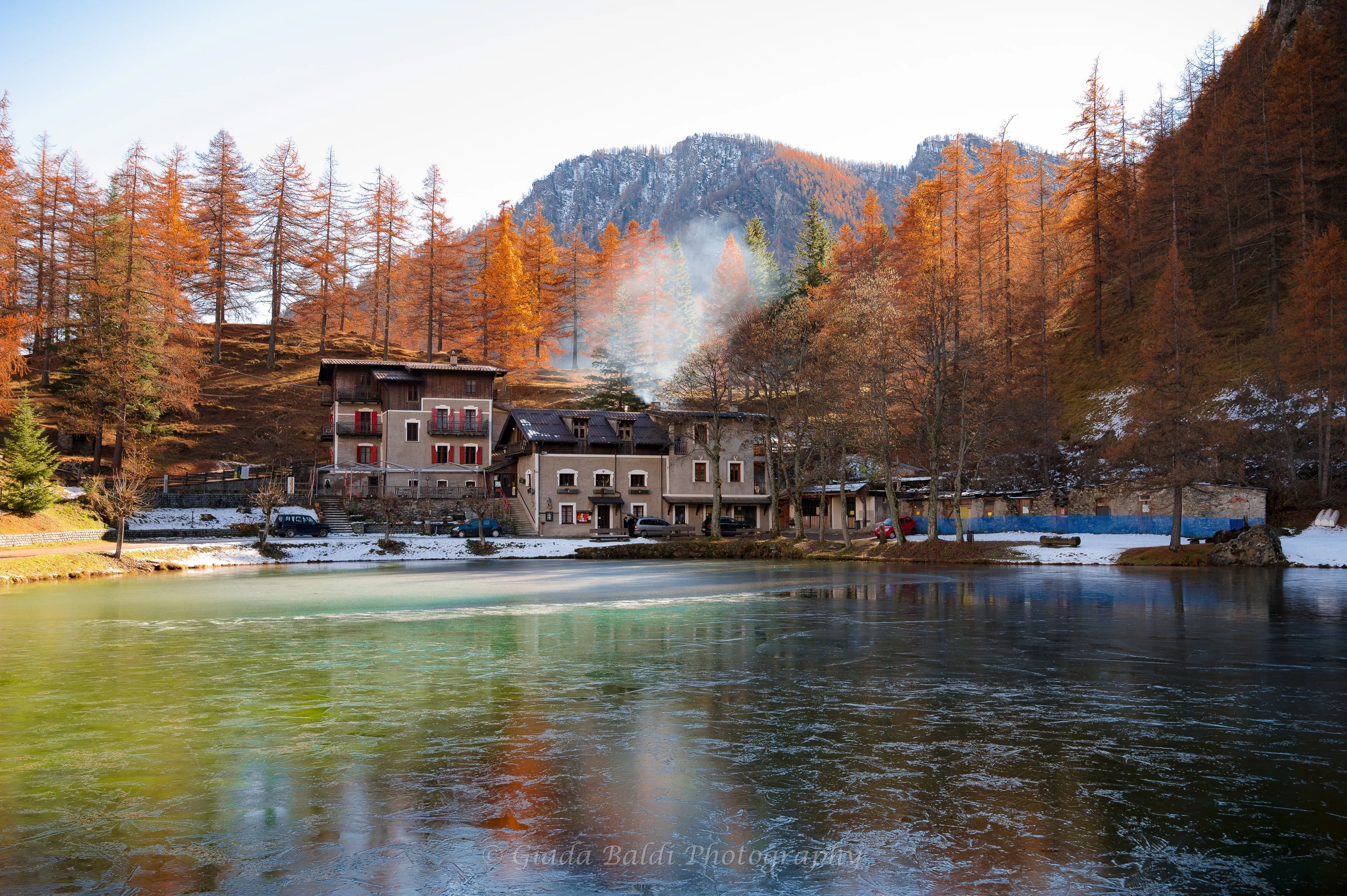 Alpine lake and refuge surrounded by autumn larches