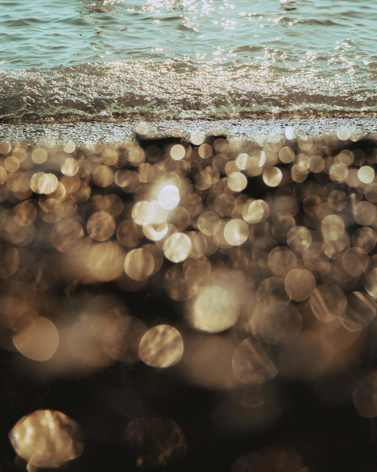 Light reflecting across sand at the water’s edge